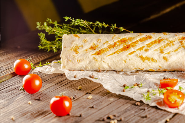 躺在一个老式的木桌上，在砧板上，多汁的烤肉沙瓦玛，有肉块，蔬菜，酱汁，深色的背景，特写，广角，全切，整个，樱桃番茄上图片下载