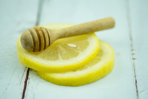 木制蜂蜜粘在柠檬片上。近距离图片下载