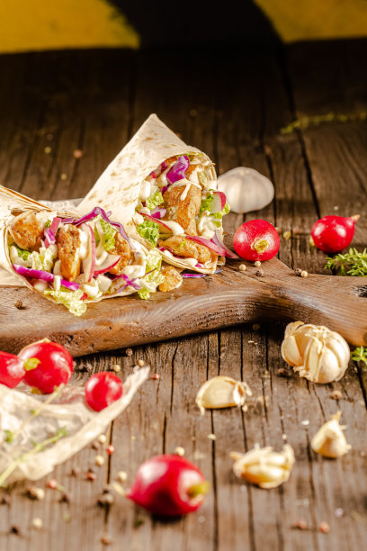 躺在一个老式的木桌上，在砧板上，多汁的烤肉沙瓦玛，有肉块，蔬菜，酱汁，深色的背景，特写，广角，全切，整个，樱桃番茄上图片下载