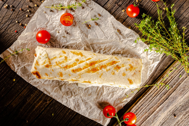 躺在一个老式的木桌上，在砧板上，多汁的烤肉沙瓦玛，有肉块，蔬菜，酱汁，深色的背景，特写，广角，全切，整个，樱桃番茄上图片下载