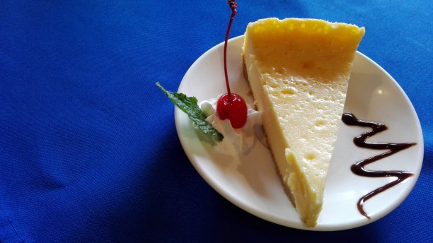 蓝色背景的白色盘子上的奶酪蛋糕图片下载