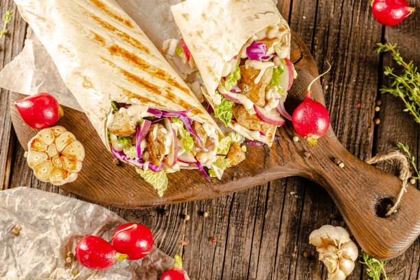 躺在一个老式的木桌上，在砧板上，多汁的烤肉沙瓦玛，有肉块，蔬菜，酱汁，深色的背景，特写，广角，全切，整个，樱桃番茄上图片下载