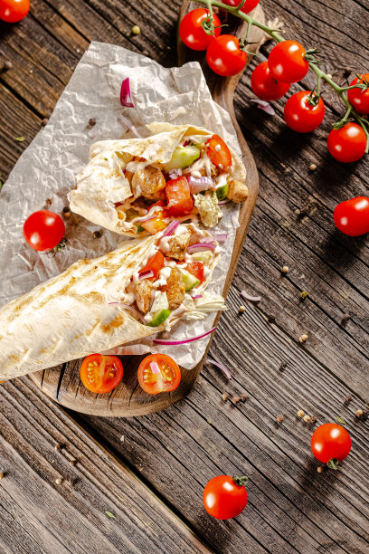 躺在一个老式的木桌上，在砧板上，多汁的烤肉沙瓦玛，有肉块，蔬菜，酱汁，深色的背景，特写，广角，全切，整个，樱桃番茄上图片下载