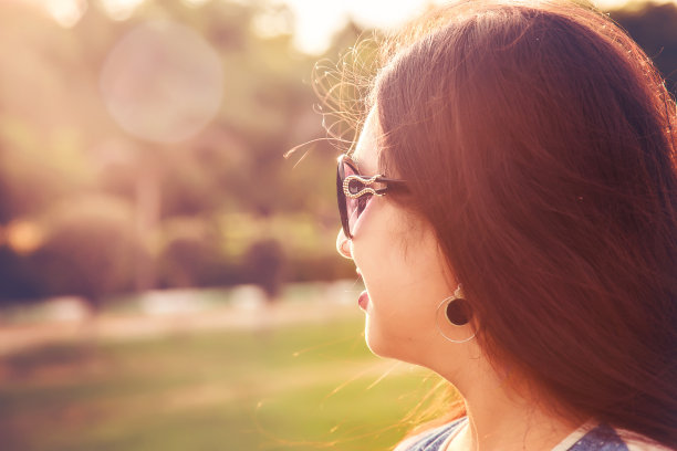年轻女子戴着太阳镜看日落图片下载