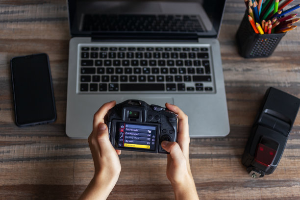 摄影师或库存摄影概念，数码黑色相机在手提电脑附近从上面，平铺书桌图片下载