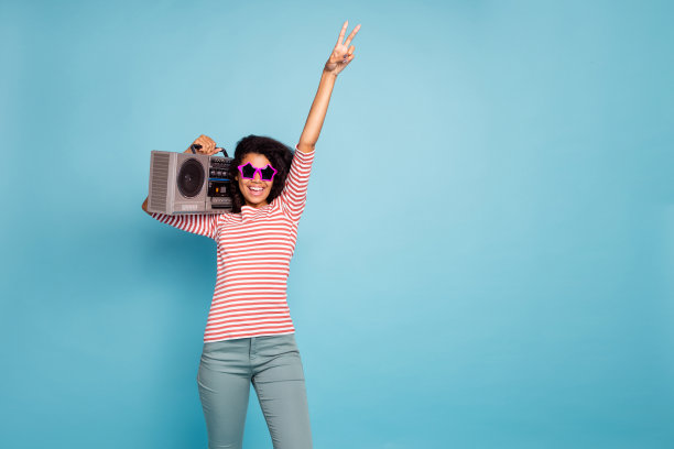 有趣的深色皮肤女士的照片显示v-sign持有凉爽的古董录音机在肩膀上准备开始派对穿太阳眼镜休闲衣服孤立的柔和的蓝色背景图片下载