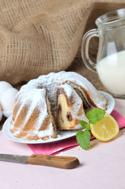 切片自制大理石蛋糕撒上糖，柠檬，梅利莎，牛奶，鸡蛋和黄油-垂直照片图片下载