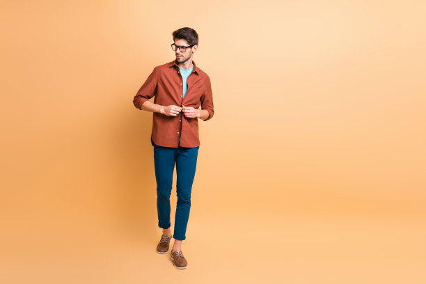 全身尺寸的观点，他很好，有吸引力的时尚内容，深色头发的家伙领导人，系衬衫上的纽扣，行走孤立的米色柔和的背景图片下载