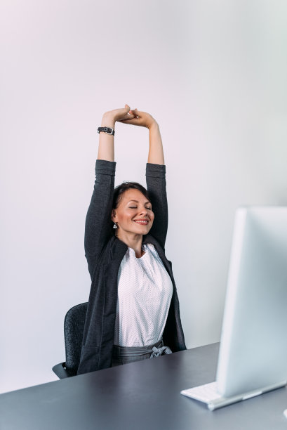 满意的年轻女商人放松伸展她的手。图片下载