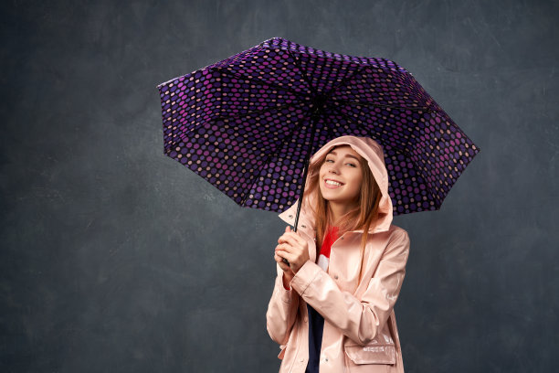 女孩在雨中穿着雨衣，拿着雨伞图片下载