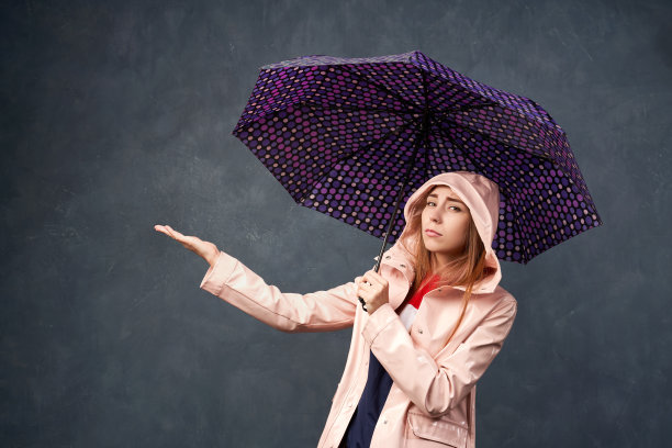 女孩在雨中穿着雨衣，拿着雨伞图片下载