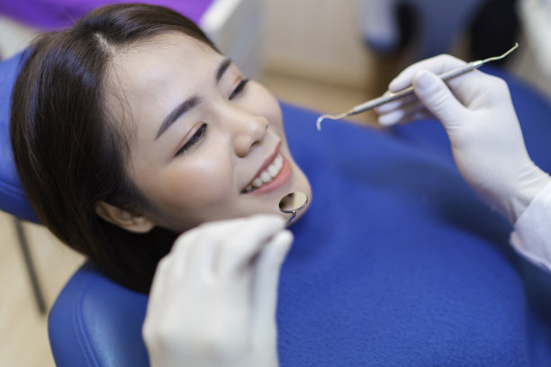 近距离微笑的妇女牙齿检查牙医检查通过挖掘机在诊所她的病人图片下载