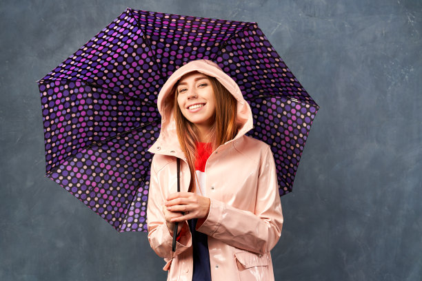女孩在雨中穿着雨衣，拿着雨伞图片下载