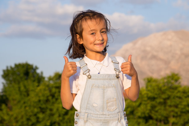 惊讶的女孩的肖像看着相机，微笑的面部表情和愉快的女孩手势拇指向上图片下载