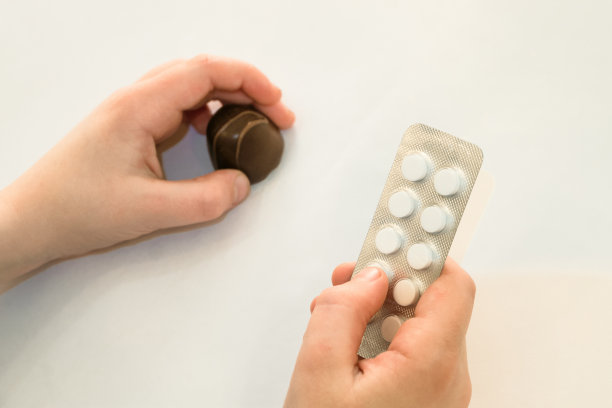 甜食和糖的危害。孩子一手拿着一包药丸和巧克力糖。有选择的集中在一只手上的药丸。图片下载