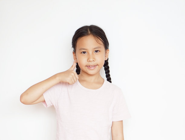 亚洲小女孩竖起大拇指站在白色的背景上图片下载
