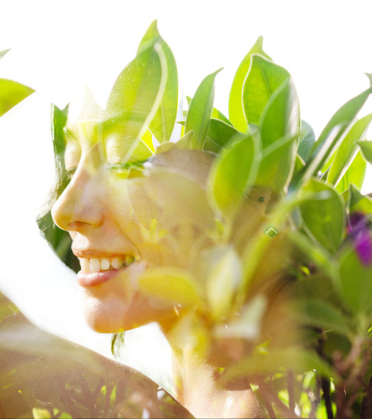 一个健康微笑的女人的侧面照片和明亮的绿色热带树叶的双重曝光图片下载