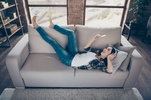 高角度全身观照片的漂亮女士拿着电话听耳罩选择电影看躺着舒适的沙发穿休闲装公寓室内图片下载