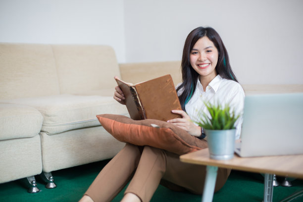 年轻的亚洲女性正在使用电脑、书籍、电话、账单、现金和计算器。在她家里图片下载