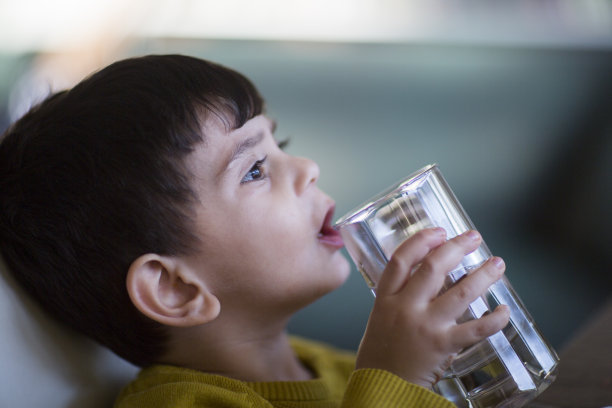 快乐快乐的男孩正在用玻璃杯喝水图片下载