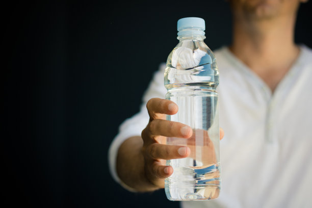一个不认识的人拿着一瓶水。图片下载