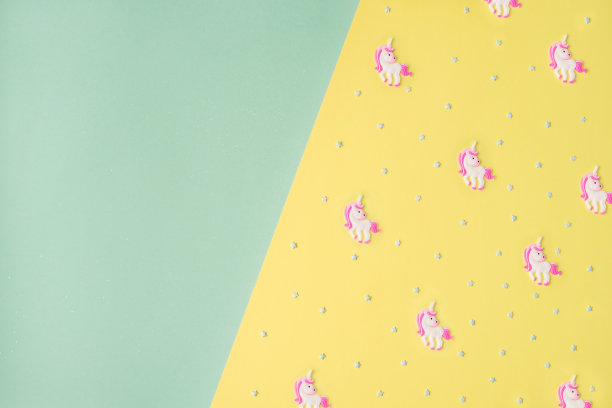 黄色薄荷背景下的蓝色星星和粉色独角兽。图片下载