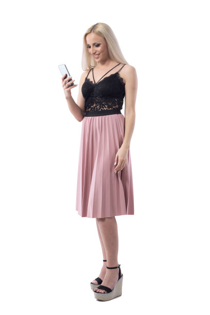 快乐的微笑轻松年轻的金发女人上网使用智能手机在优雅的衣服。图片下载