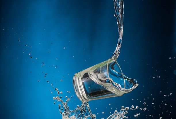 倒着伏特加的玻璃杯，喷在蓝色背景上图片下载