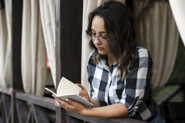 女孩在夏日露台上的咖啡馆里看书图片下载
