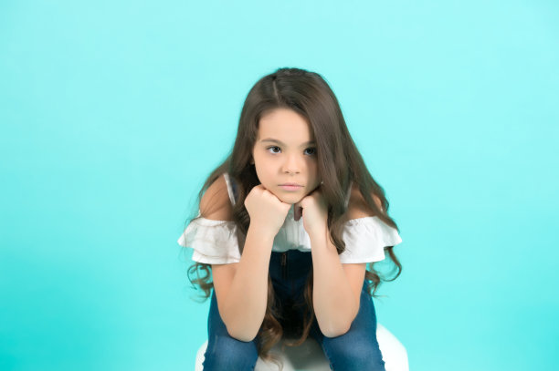 孩子把下巴撑在蓝色的背景上图片下载