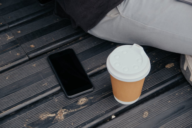 一个自由职业者坐在城市里，带着笔记本手机摄像头，喝着咖啡或茶，戴着耳机图片下载