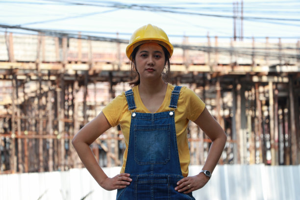 女土木工程师或建筑师，头戴黄色头盔，腰叉站立。图片下载