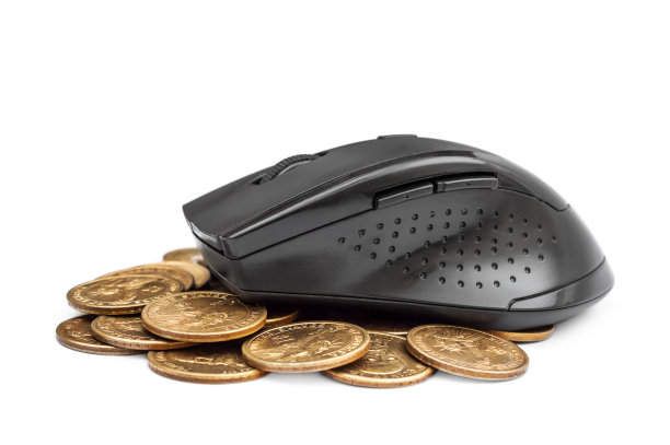电脑鼠标放在一堆金币上。图片下载