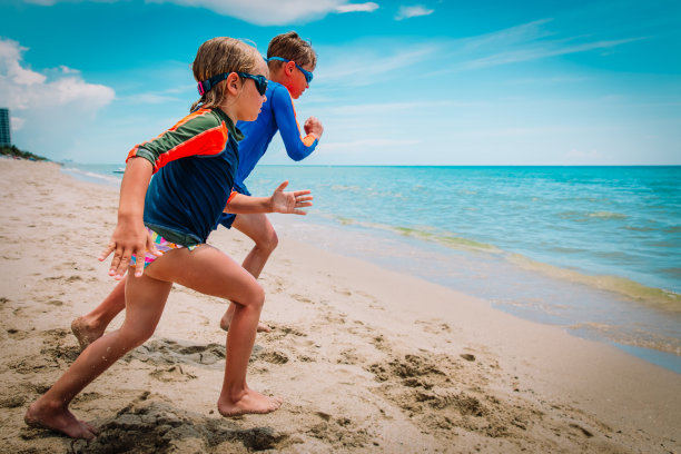 快乐的男孩和女孩在海滩上跑步游泳图片下载