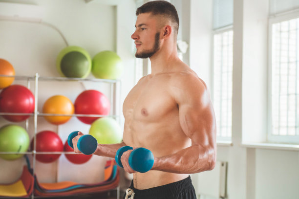 健身教练在运动室内的背景。男性模特与肌肉健康和苗条的身体图片下载