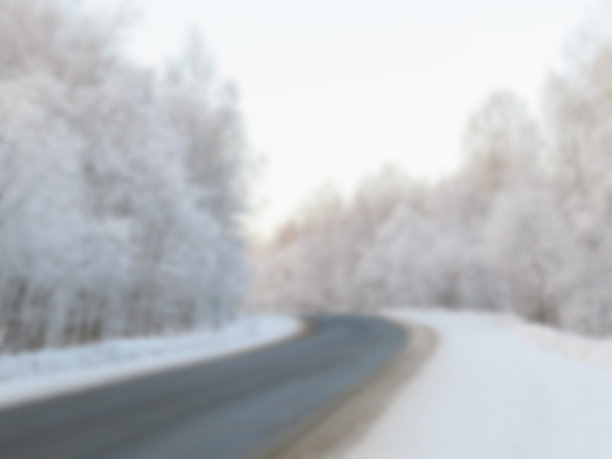 模糊的道路穿过积雪的树林。图片下载
