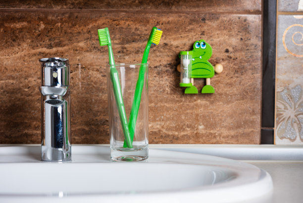 原装和正畸牙刷玻璃和定时器在墙上靠浴室。健康的生活方式。有选择性的重点图片下载