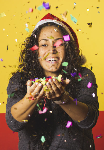 戴着圣诞老人帽、撒着五彩纸屑的女人图片下载
