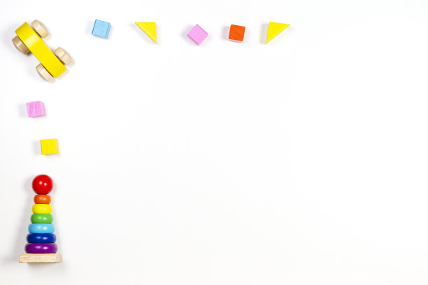婴儿玩具背景。木制玩具车，婴儿堆叠环金字塔和彩色积木在白色的桌子上图片下载