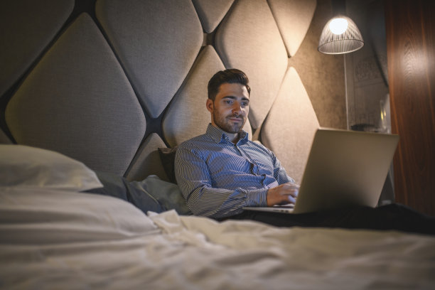 年轻的商务主管躺在酒店房间里使用笔记本电脑图片下载