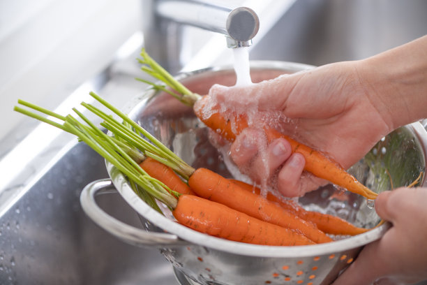 在水槽里洗胡萝卜的女人。图片下载