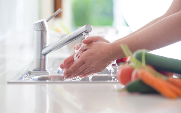 一个女人在厨房水槽边洗手。图片下载