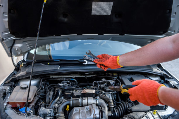 双手戴上防护手套，用扳手对准汽车发动机图片下载
