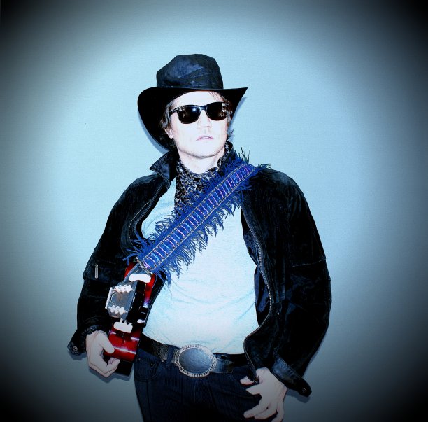 酷酷的乡村歌手和吉他手戴着一顶帽子与原声吉他站在一个彩色的背景。图片下载