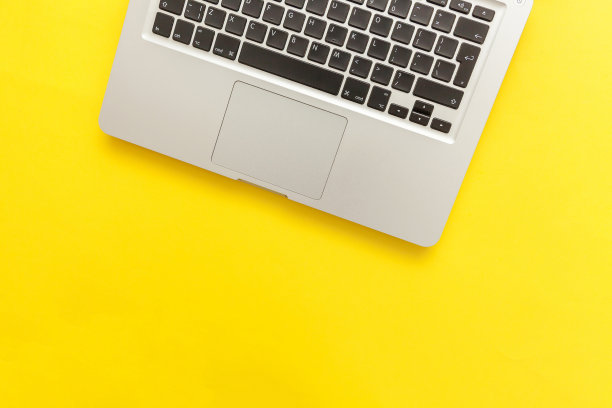 键盘笔记本电脑隔离在黄色的桌面背景。现代信息技术和软件的发展图片下载