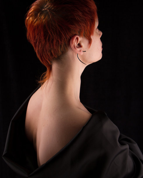 一个红色头发的中年妇女赤裸的肩膀在一个黑色的背景，选择性的焦点图片下载