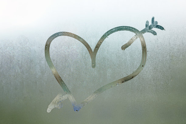 爱的心与箭在湿窗上。特写雾蒙蒙的玻璃背景图片下载