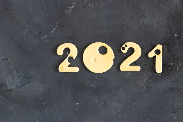 在黑色对比粉笔板的背景上，用带有孔的奶酪制作的2021图，象征着适当的营养和教育。横向框架。圣诞节和新年的概念图片下载