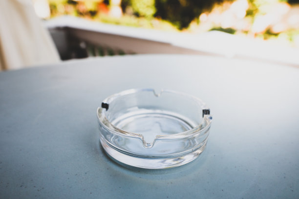 浅景深的现场图像与一个空的玻璃烟灰缸在桌子上停止吸烟的概念。图片下载