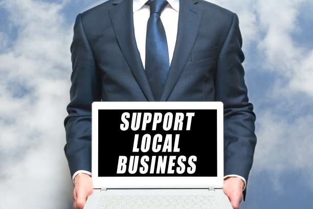 当地的商业支持人员在手提电脑上举着标牌，以促进当地的小企业图片下载